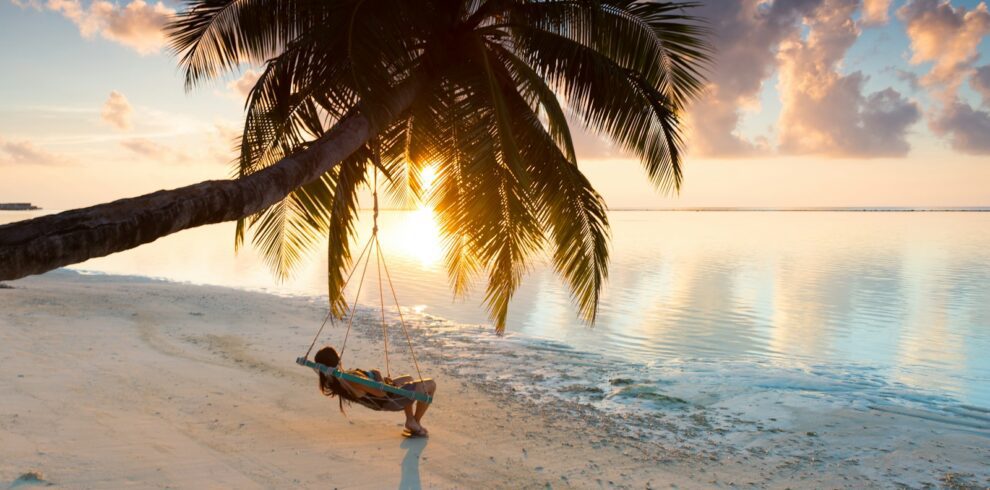 person swinging on hammock hanged on coconut tree near sea