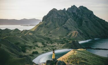 woman standing on mountain near body of water
