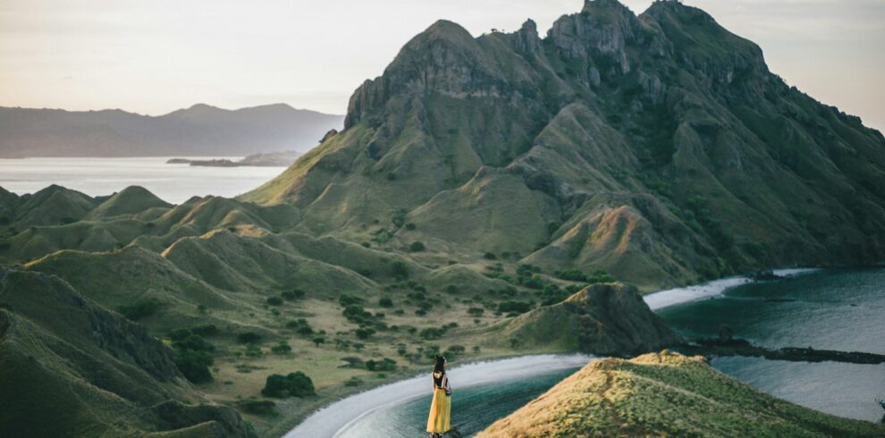 woman standing on mountain near body of water